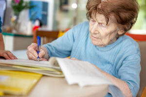 elderly woman signing papers
