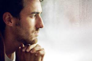 man looking out the window depressed