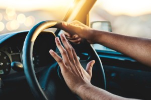 young driver hands laying on car horn