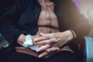 folded hands of an elderly woman in wheelchair