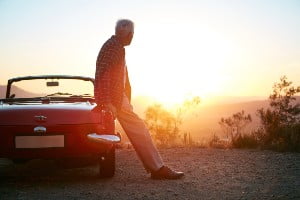 old man standing by car at sunset