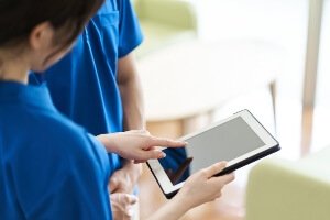 female in scrubs looking at notes on tablet