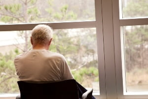 elderly man sitting in wheelchair facing a window