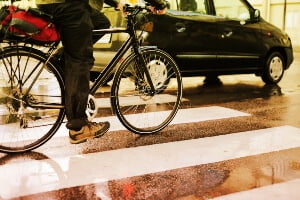 stock img - cyclist riding beside mini van on wet city street