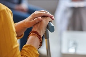 stock image of the hands of an elderly woman resting on a walking cane