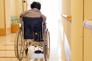 elderly woman sitting in wheelchair abandoned in hallway