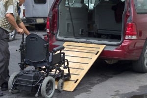 man pushing wheelchair into a van