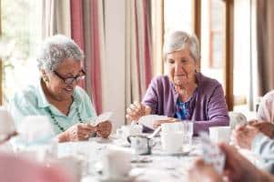 elderly women playing cards and smiling