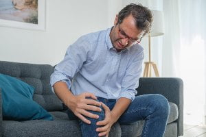 man grabbing knee in pain