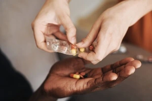 A medical practitioner giving pills to an elderly person.