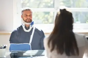 injured middle-aged man meeting with female lawyer
